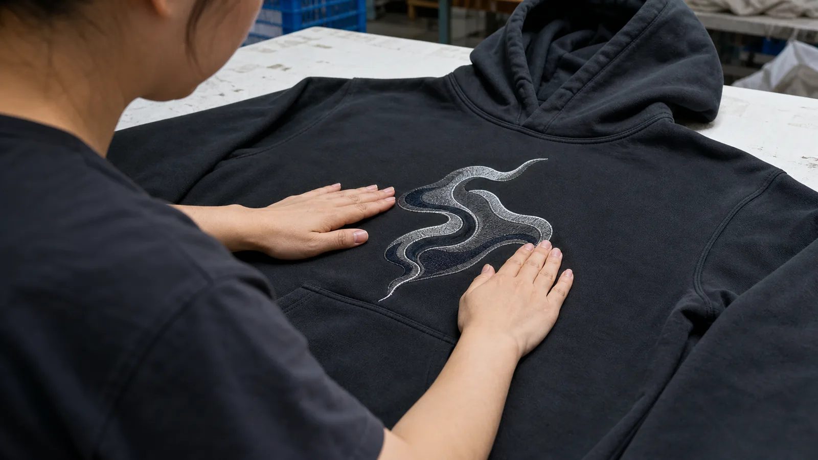 Custom Hoodie Printing Methods for Streetwear Brands Chinese apparel worker inspecting decoration on one unbranded hoodie