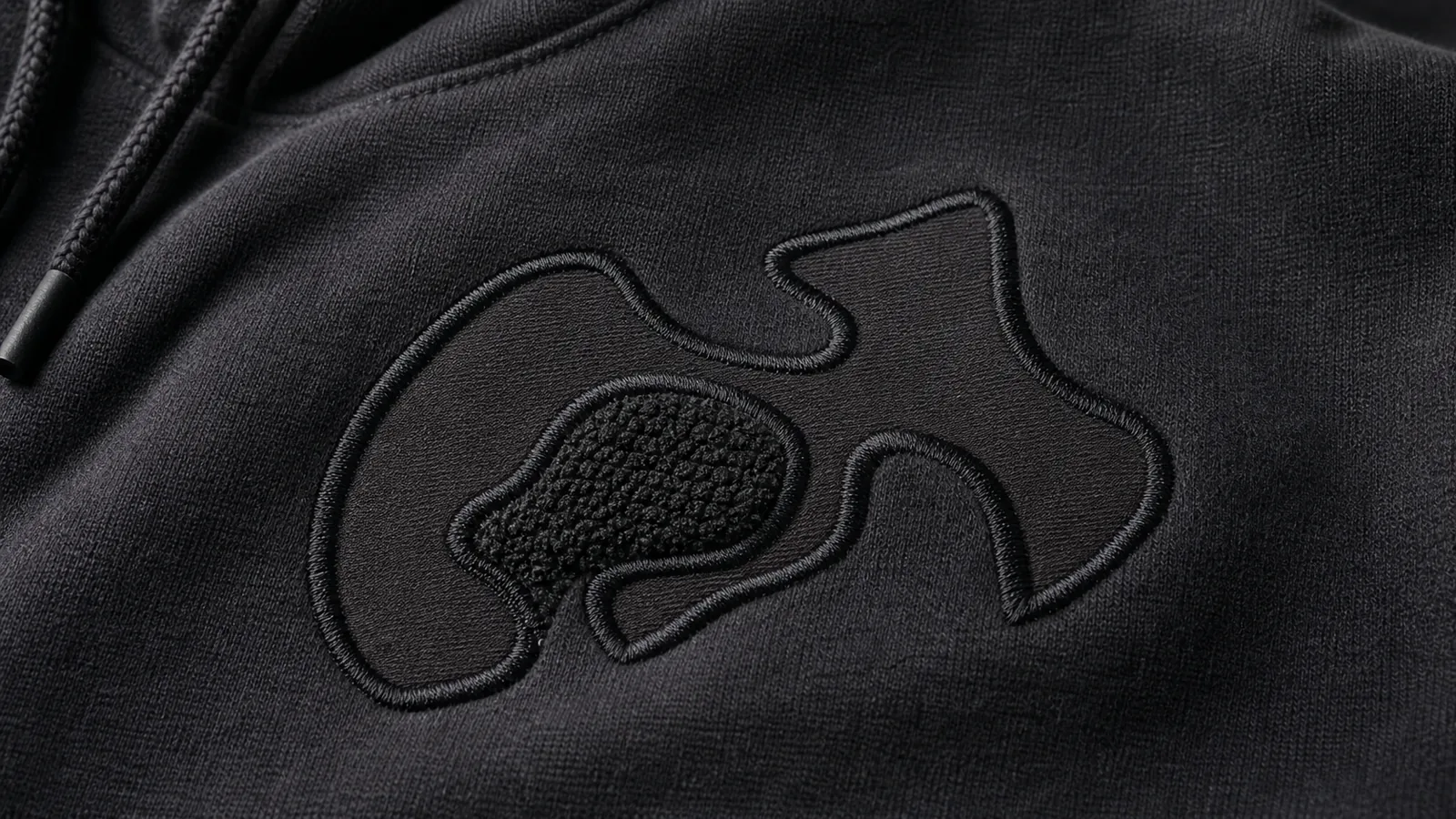 Custom Hoodie Printing Methods for Streetwear Brands Close-up of appliqué and textured embroidery on unbranded hoodie fabric