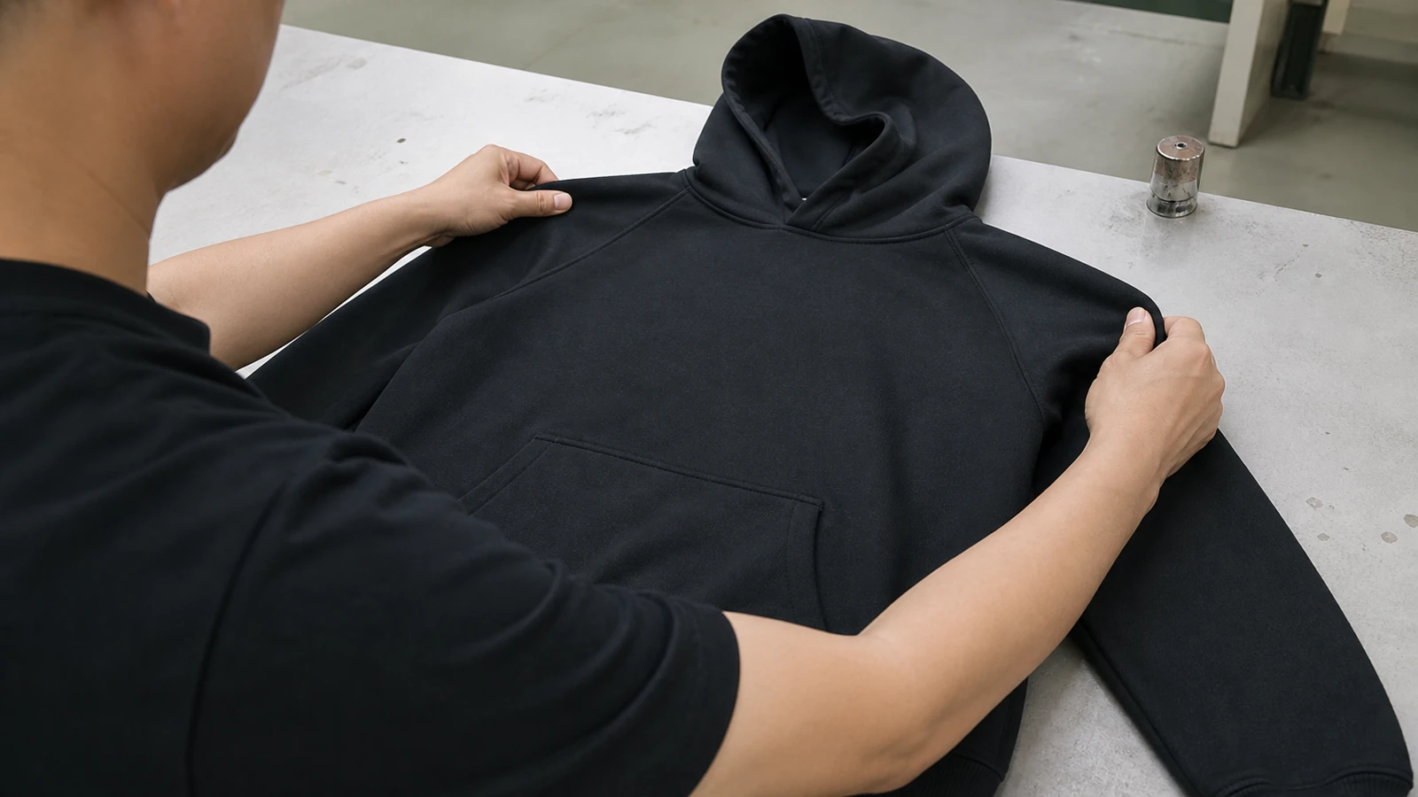 Chinese apparel worker inspecting the fit and details of one hoodie sample
