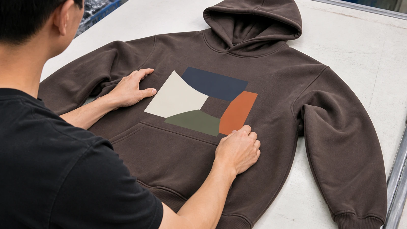 Apparel worker checking artwork placement on an unbranded hoodie