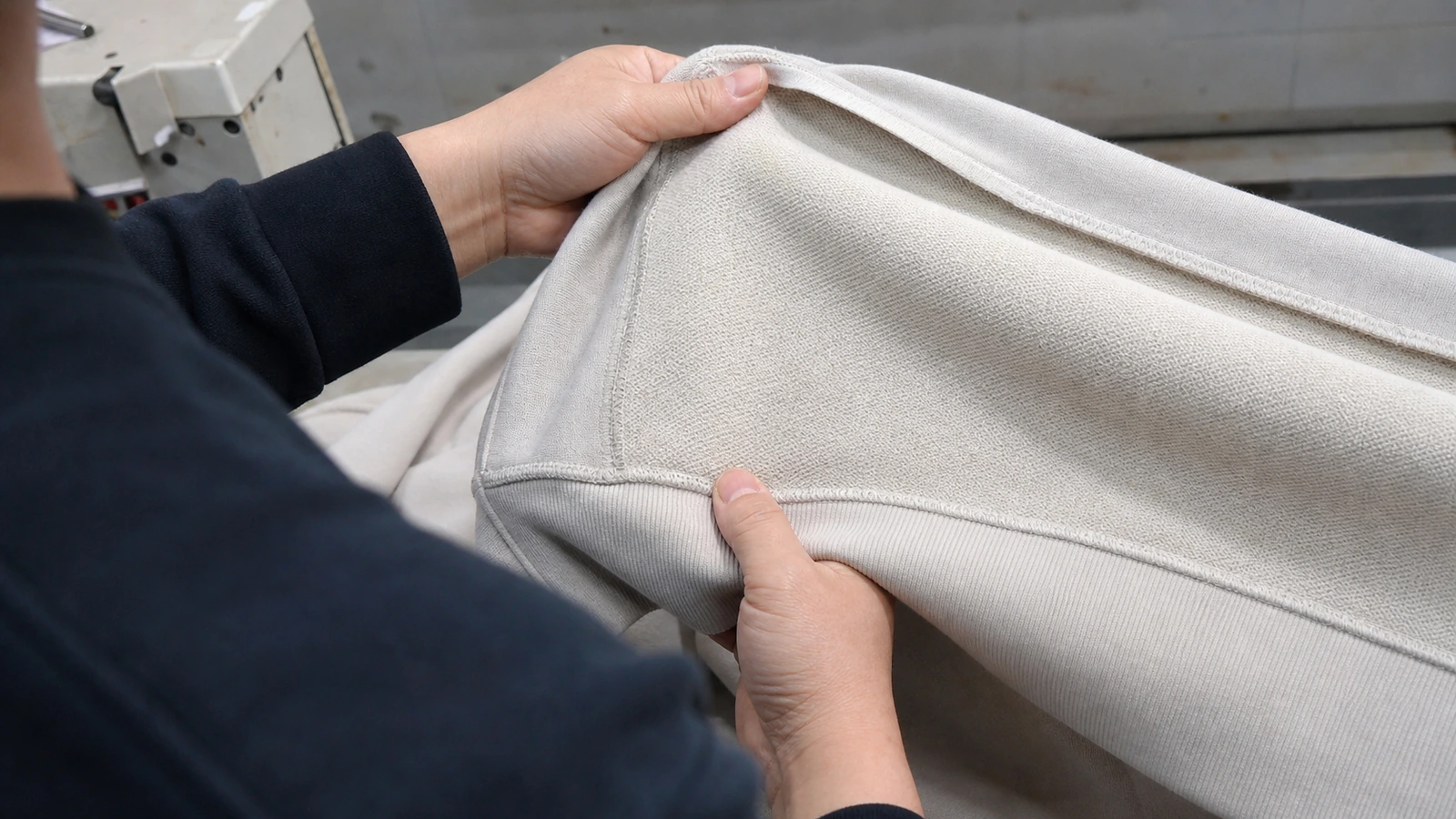 What Is the Difference Between Fleece and French Terry Hoodies? Chinese apparel worker inspecting the inner surface and stretch of hoodie fabric