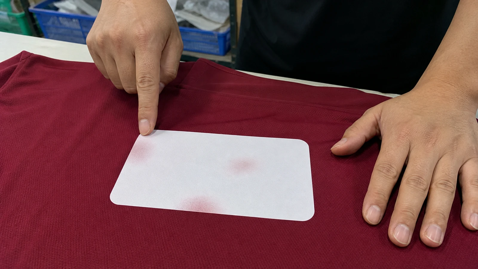 Is DTF Better on Cotton or Polyester? Apparel worker inspecting a light DTF sample on dark polyester fabric